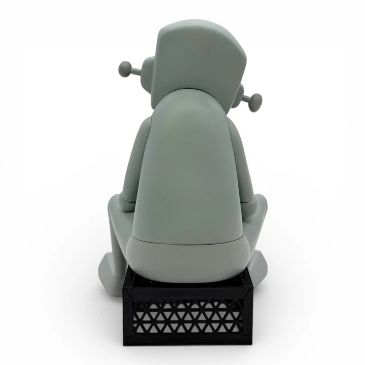 The Thinker vinyl figure seated on a black crate, back view